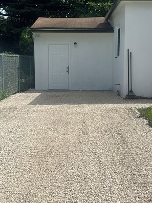 Eine weiße Garage mit geschlossenem Tor, einem Schotterweg und einem Metallzaun im Hintergrund.