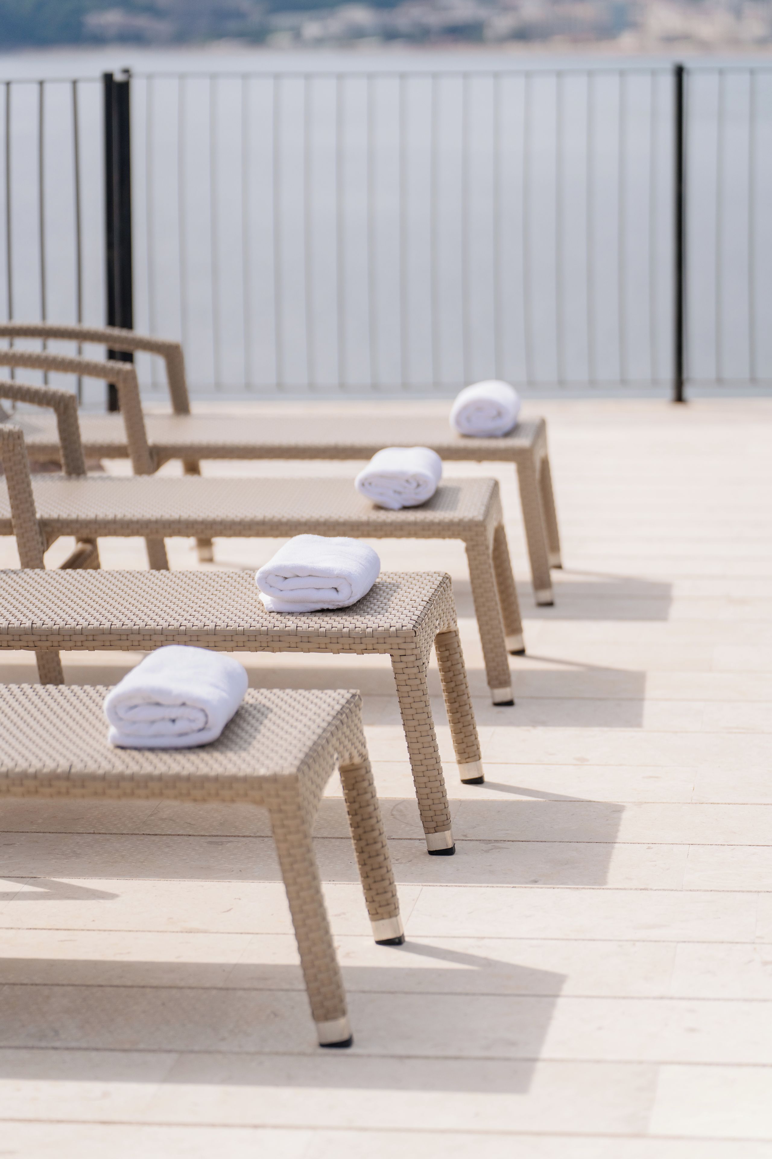 Una hilera de sillones de mimbre con toallas, dispuestas en una terraza de madera.