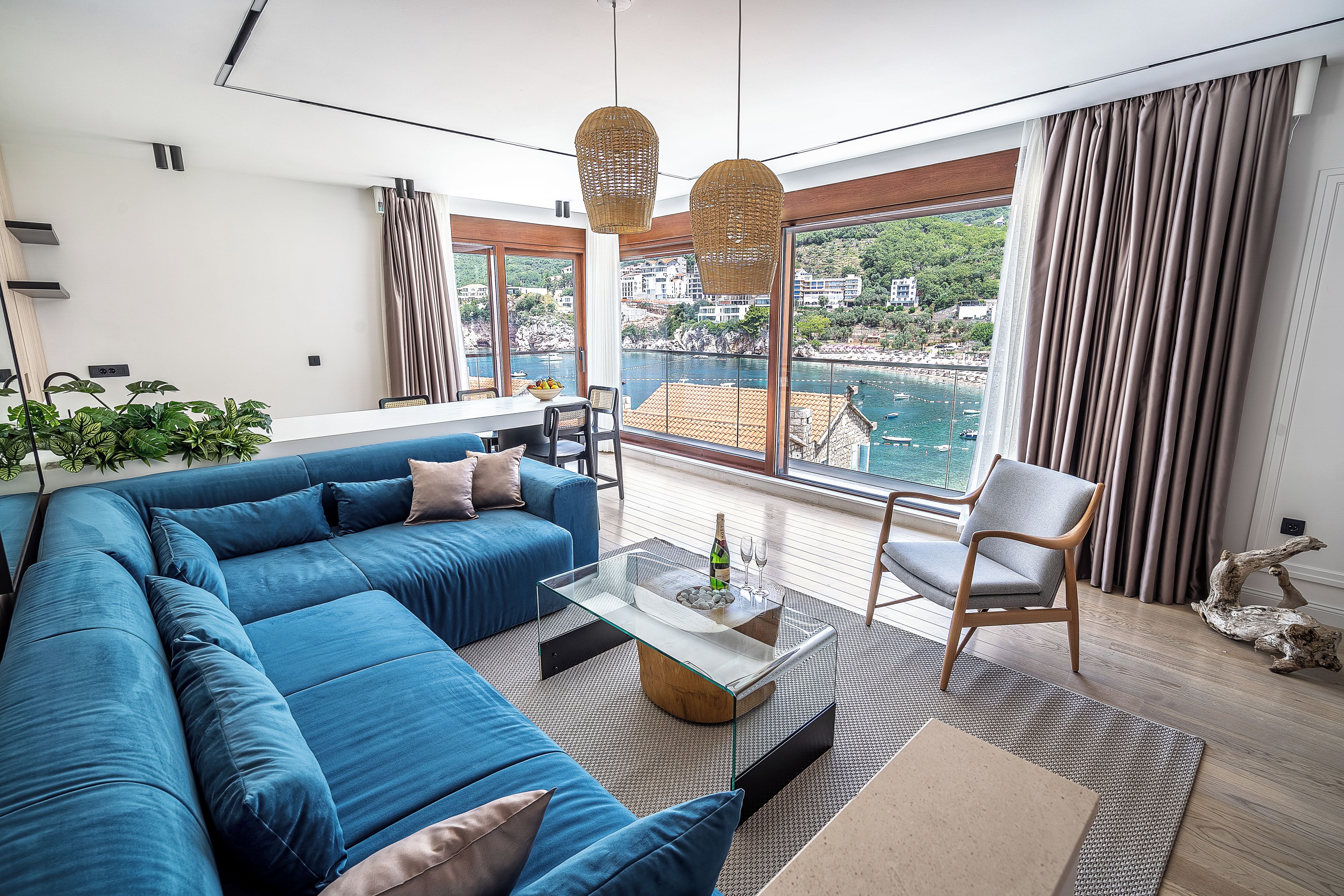 Una sala de estar moderna con un sofá azul, una mesa de centro de vidrio y vista al mar.