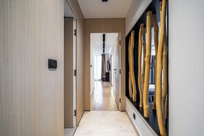 Un pasillo con paneles de madera, una lámpara moderna y una gran escultura de madera.