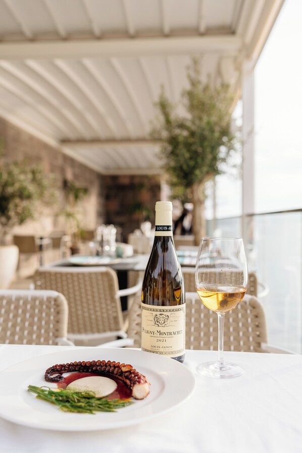 A table with a bottle of wine, a glass of wine, and a plate of food.