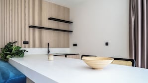 Una cocina moderna con encimera blanca, salpicadero de madera y una silla negra.