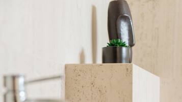 Un lavabo de salle de bain avec un robinet moderne, une petite plante en pot et un distributeur de savon.