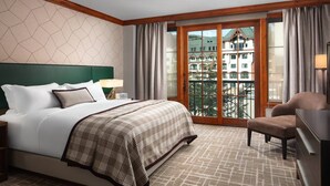 Een hotelkamer met een groot bed, een stoel, een bureau en uitzicht op een gebouw door een glazen deur.