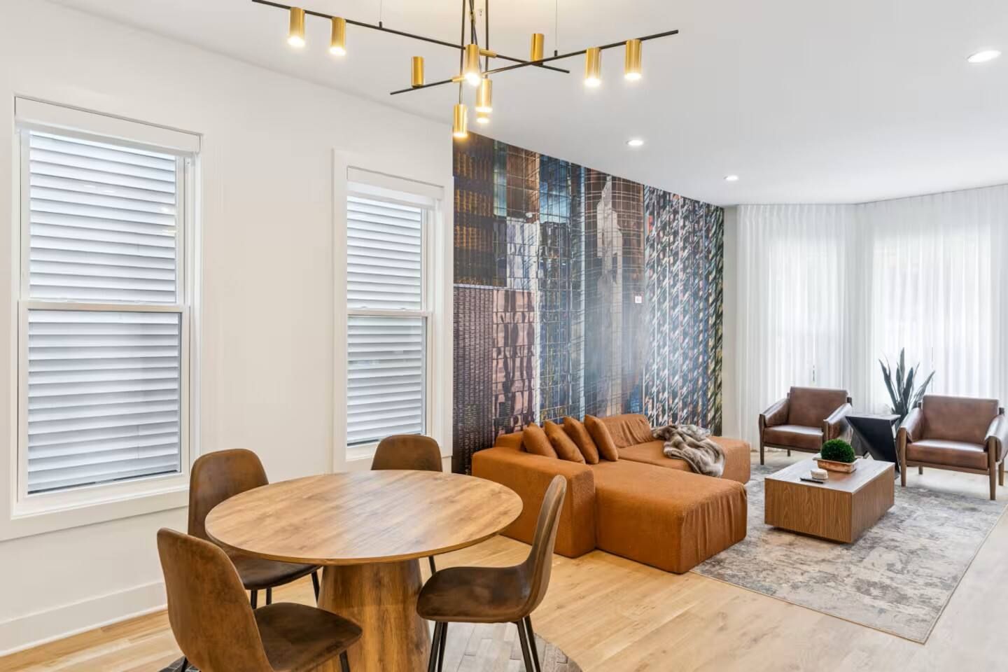 A modern living room with a round wooden table, two sofas, and leather armchairs.