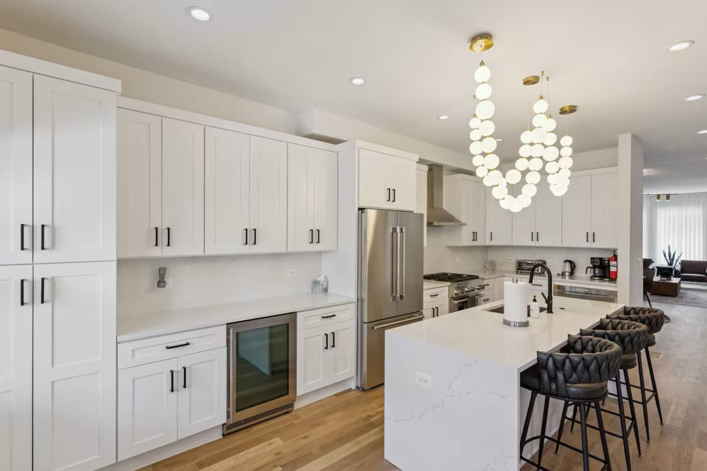 A modern kitchen with white cabinetry, a central island, and a stainless steel refrigerator.