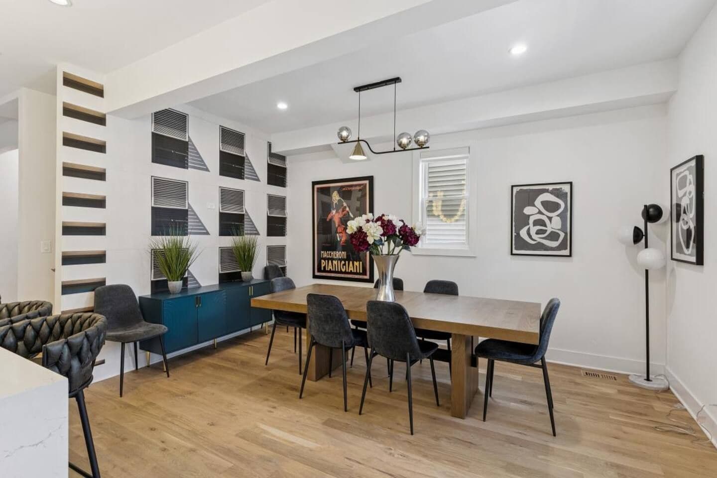 A modern dining area with a wooden table, black chairs, and a blue cabinet.
