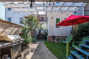 A backyard with a barbecue grill, patio furniture, and a pergola with string lights. - Sojourn 1 Block to Metro, Cap Hill Garden Flat (Washington)