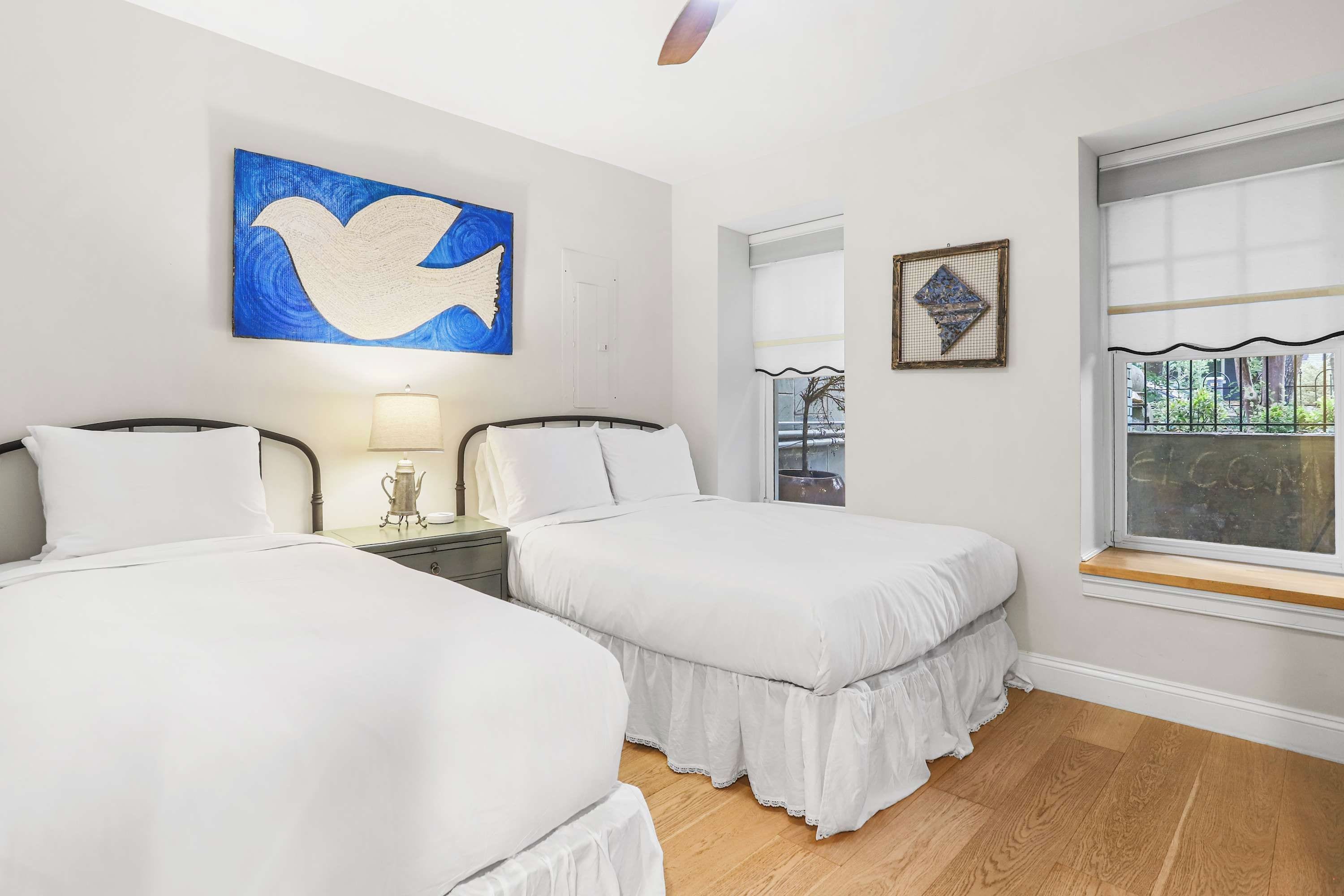 A hotel room with two beds, a large window, and artwork on the walls.