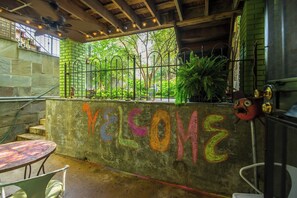 An outdoor seating area with a concrete wall featuring colorful graffiti, a metal fence, and potted plants. - Sojourn 1 Block to Metro, Cap Hill Garden Flat (Washington)