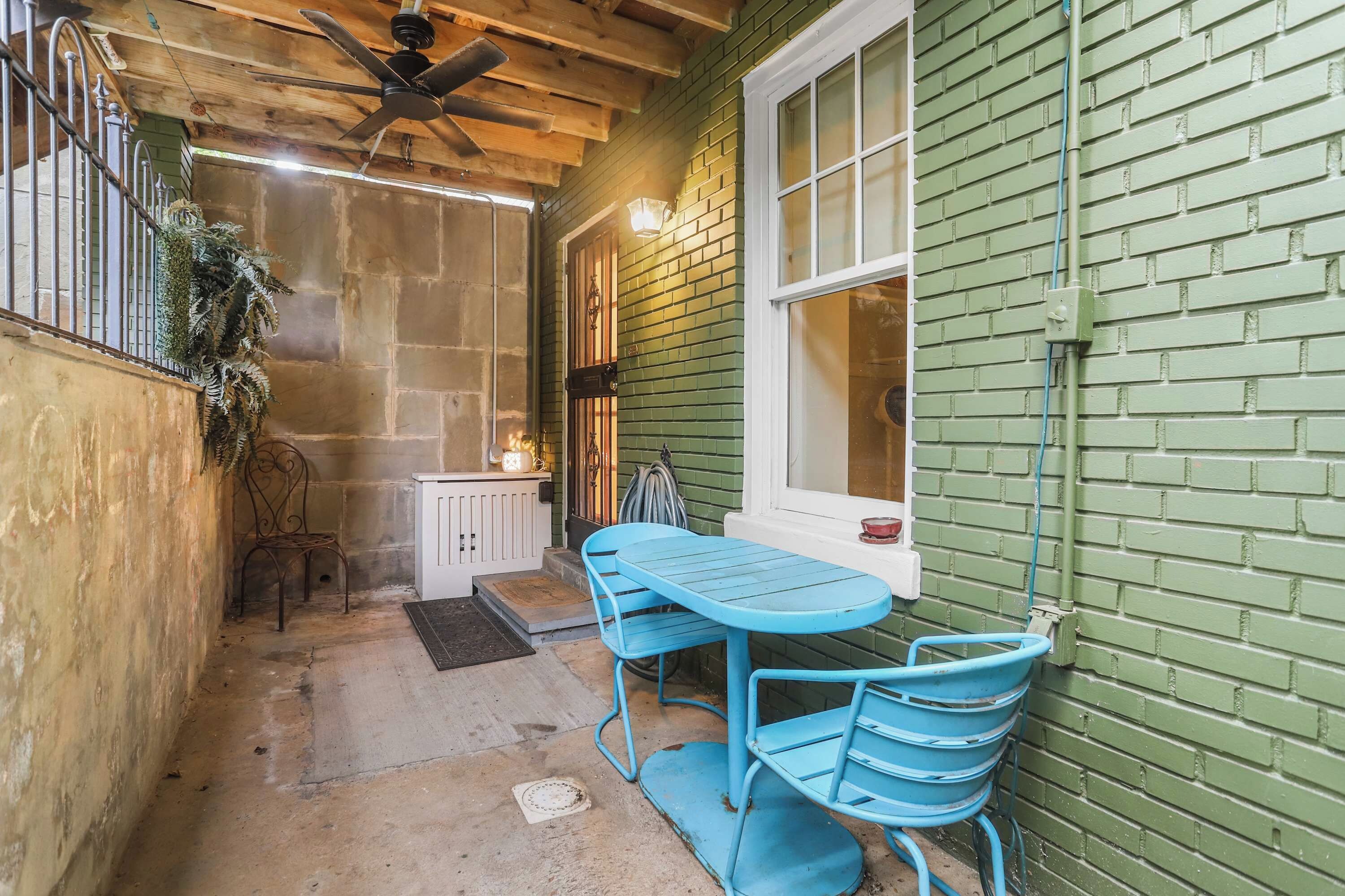 Un patio con mesa y sillas, un ventilador de techo y una ventana con vistas.