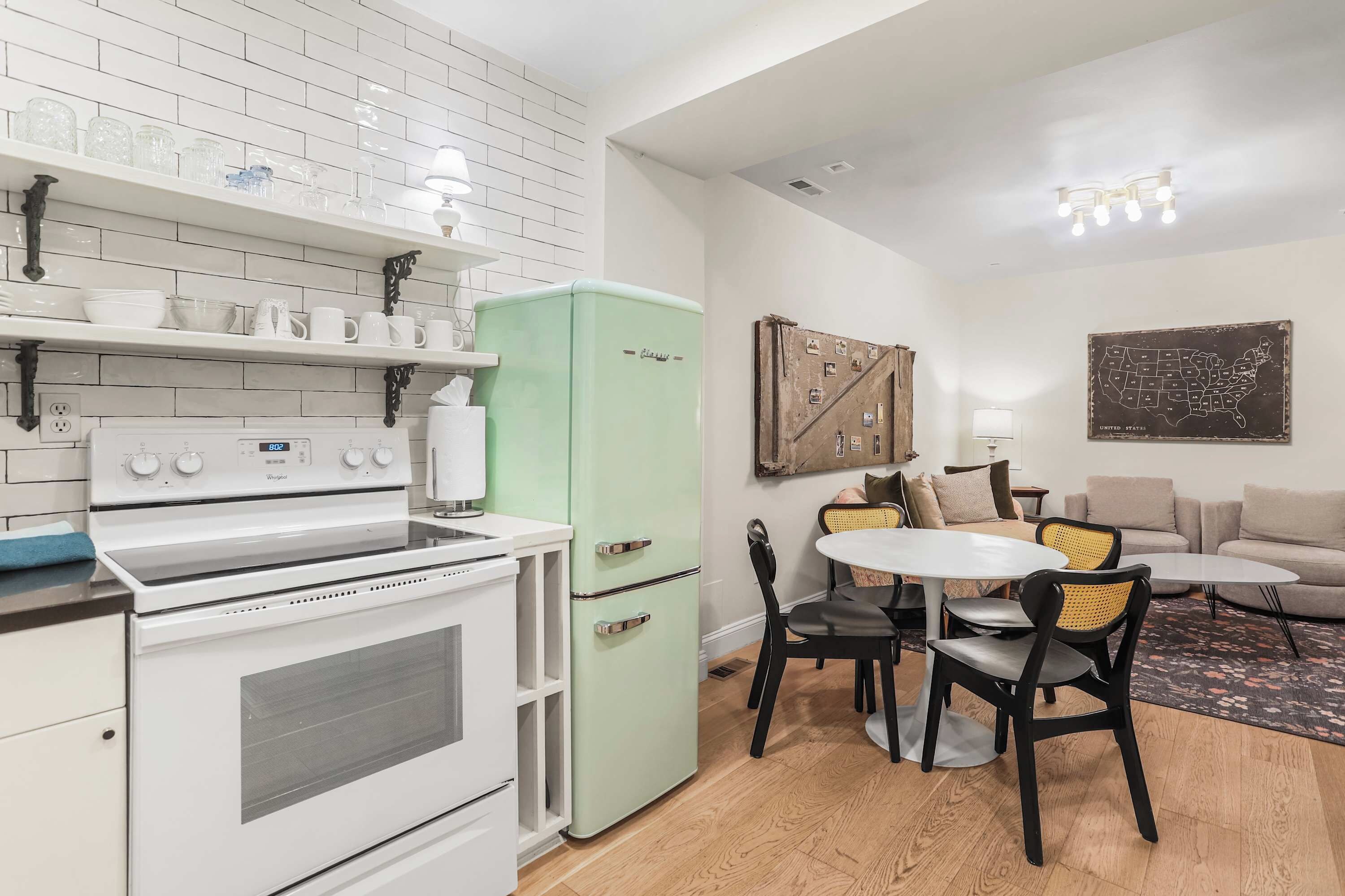 Cocina compacta con estufa blanca, refrigerador verde y comedor con mesa redonda y sillas.