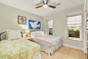A bedroom with two beds, a ceiling fan, artwork, and a window with a view. - Sojourn 1 Block to Metro, Cap Hill Garden Flat (Washington)