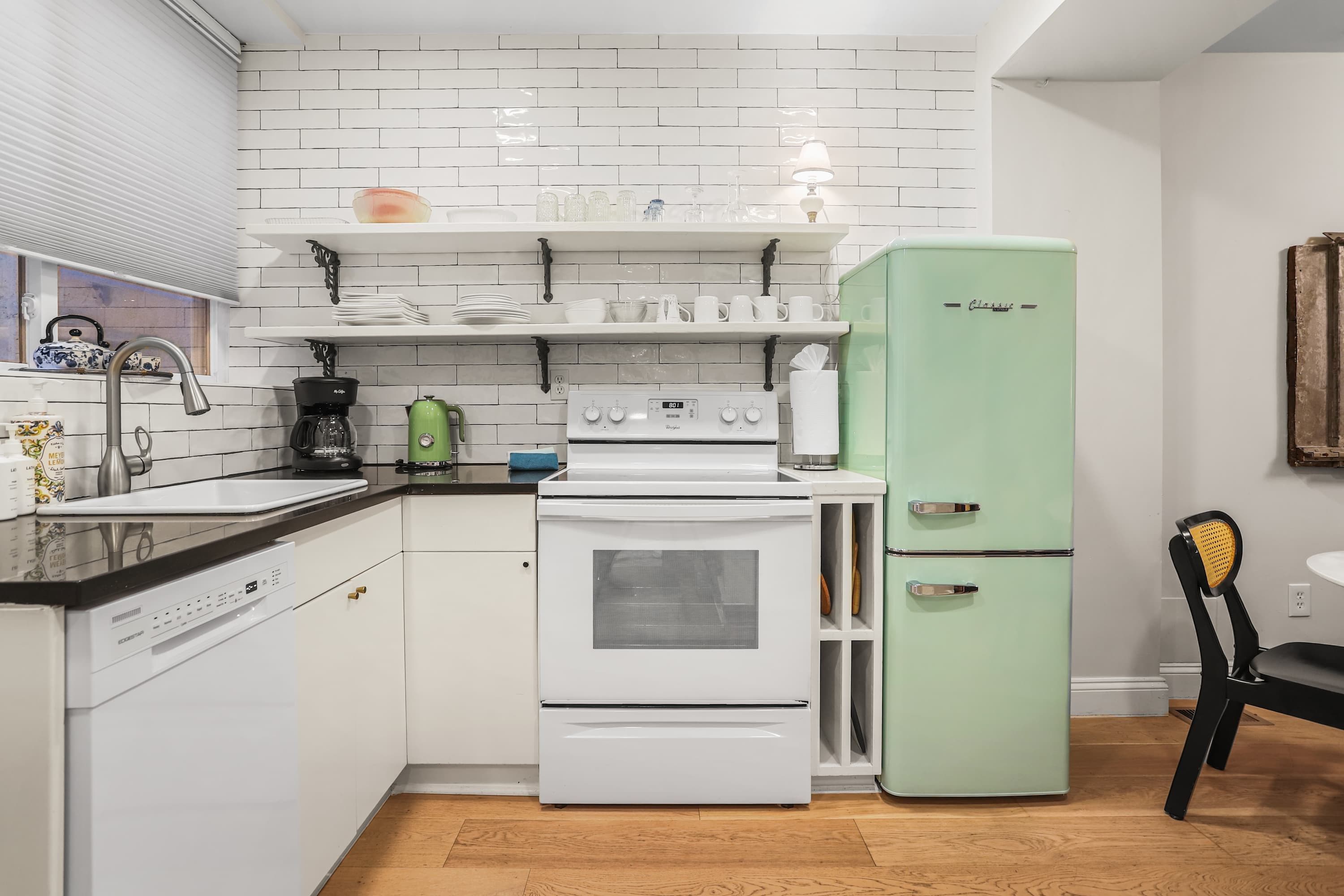 A compact kitchen with white appliances, a coffee maker, and a green refrigerator.
