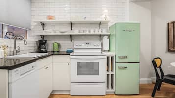 A compact kitchen with white appliances, a coffee maker, and a green refrigerator.