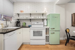 A compact kitchen with white appliances, a coffee maker, and a green refrigerator.