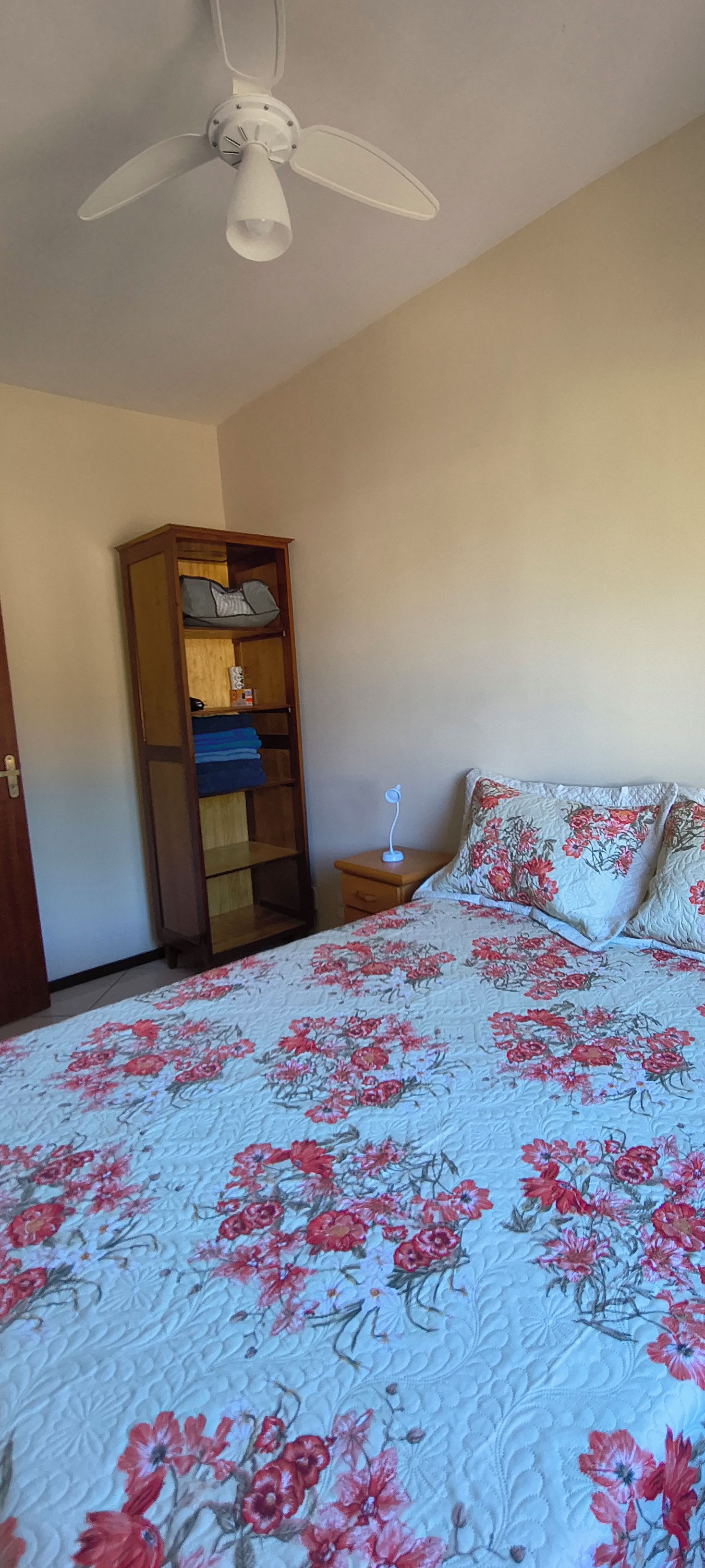 Une chambre à coucher comprenant un lit, un ventilateur de plafond, une armoire et une table de chevet.