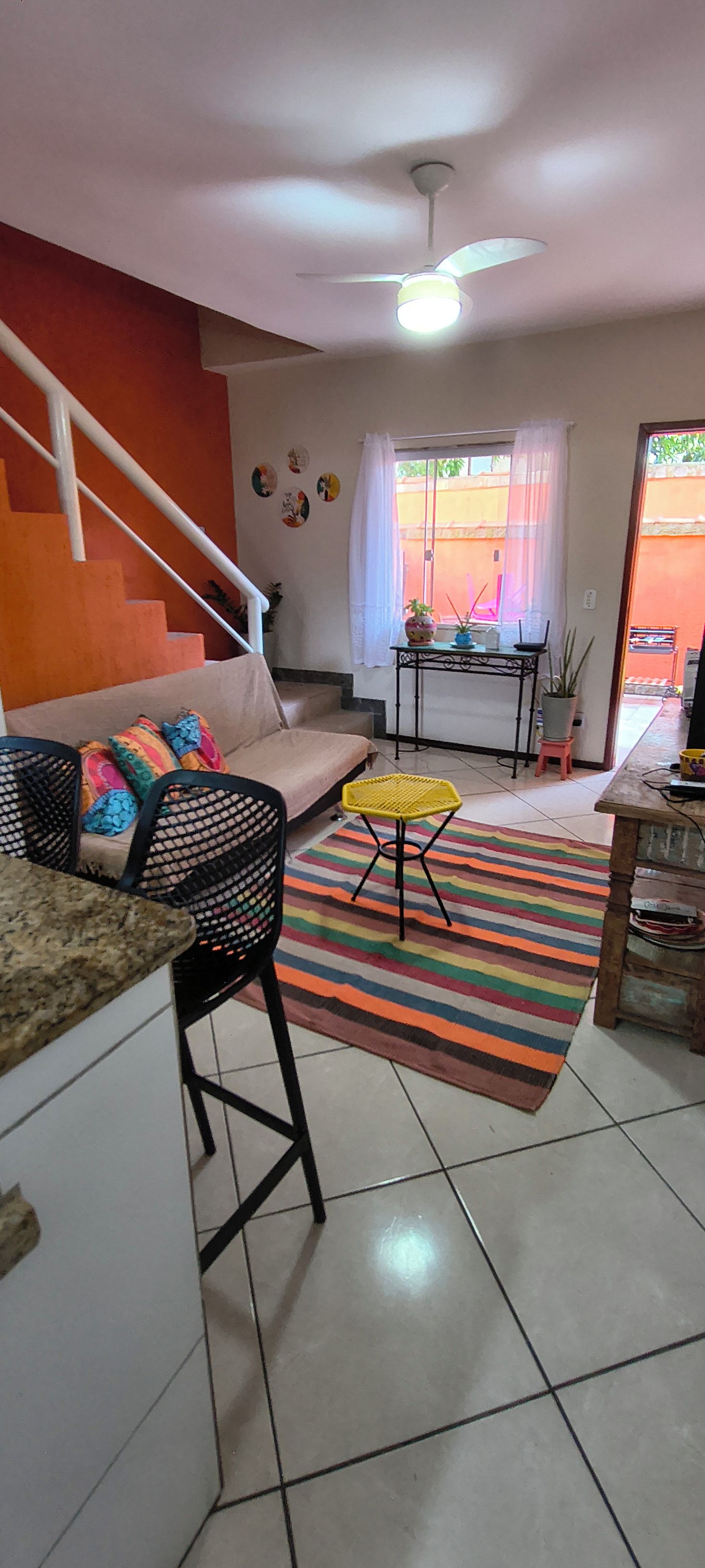 A compact living space with a kitchen area, a sofa, a dining table, and a staircase.