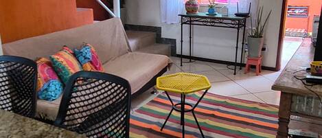 A compact living space with a kitchen area, a sofa, a dining table, and a staircase.