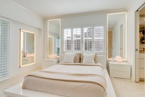 Ein Schlafzimmer mit einem großen Bett, zwei Nachttischen, einem Kleiderschrank und einem Fenster mit Jalousien.