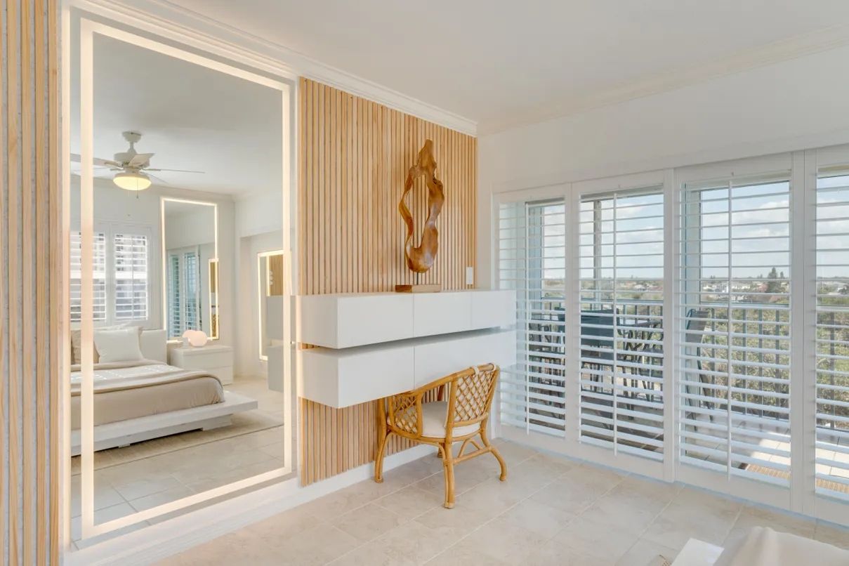 A modern bedroom with a bed, a desk, and a view through large windows.