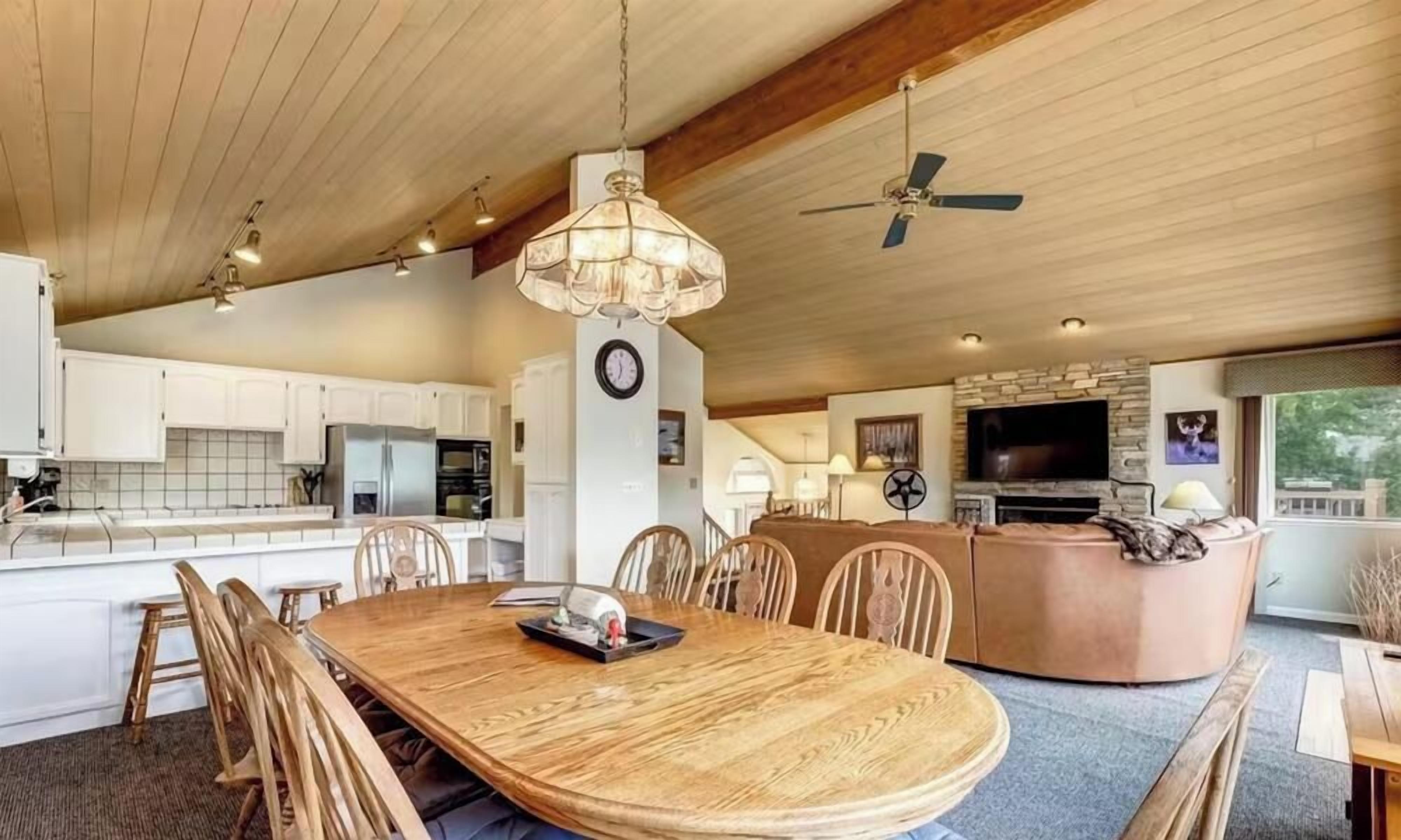 A spacious kitchen with wooden cabinets, a dining area with a large wooden table and chairs, a built-in oven, and a television.