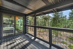 A wooden deck with a glass door leading to a bedroom with a bed and seating area. - Charming Updated Tahoe Cabin Near Heavenly | Forest Views | Two Decks (South Lake Tahoe)