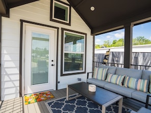 A covered porch with a gray sofa, a small table, and a colorful rug. - The Tannehill - Citrus Loft Cabin - Grill - Pool - Hot Tub - Bar - Lake - Gym (Crystal River)