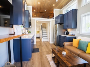 A compact kitchen with dark cabinets, a wooden countertop, and a built-in stove.