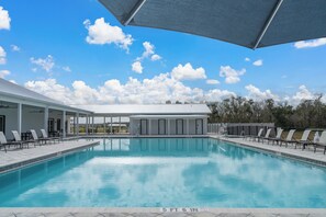A swimming pool with lounge chairs and a covered area, under a clear sky.