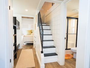 A staircase leading to a bedroom with a bed, a nightstand, and a window.