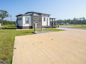 A modern single-story building with a covered porch and a small outdoor seating area. - The Tannehill - Citrus Loft Cabin - Grill - Pool - Hot Tub - Bar - Lake - Gym (Crystal River)