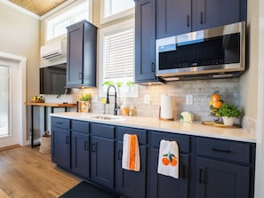 A modern kitchen with dark cabinets, a stainless steel range hood, and a built-in microwave.