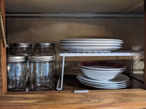 A storage area with shelves holding jars, plates, and a bowl. - Charming 2-bedroom recreational vehicle in enjoyable Sequim location (Sequim)