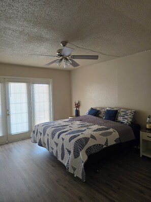 A bedroom with a bed, a ceiling fan, a nightstand, and a window with blinds. - Adorable 1-bedroom condo with AC in beautiful Runaway Bay with lake views (Runaway Bay)