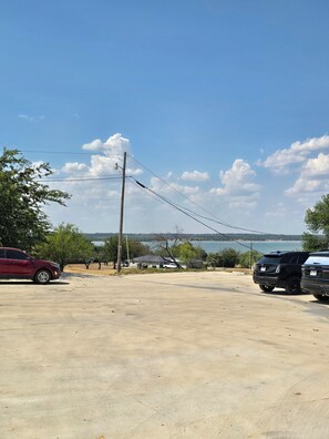 A parking lot with two cars, a clear sky, and a distant view of a body of water. - Adorable 1-bedroom condo with AC in beautiful Runaway Bay with lake views (Runaway Bay)