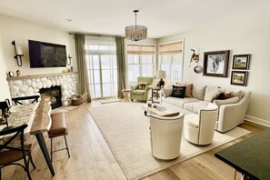 Una sala de estar con chimenea, un comedor con mesa y sillas, y un sofá.