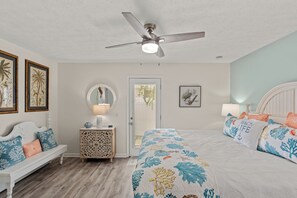 Ein Schlafzimmer mit Bett, einer Bank, einem Nachttisch, einem Deckenventilator und Kunstwerken an den Wänden.