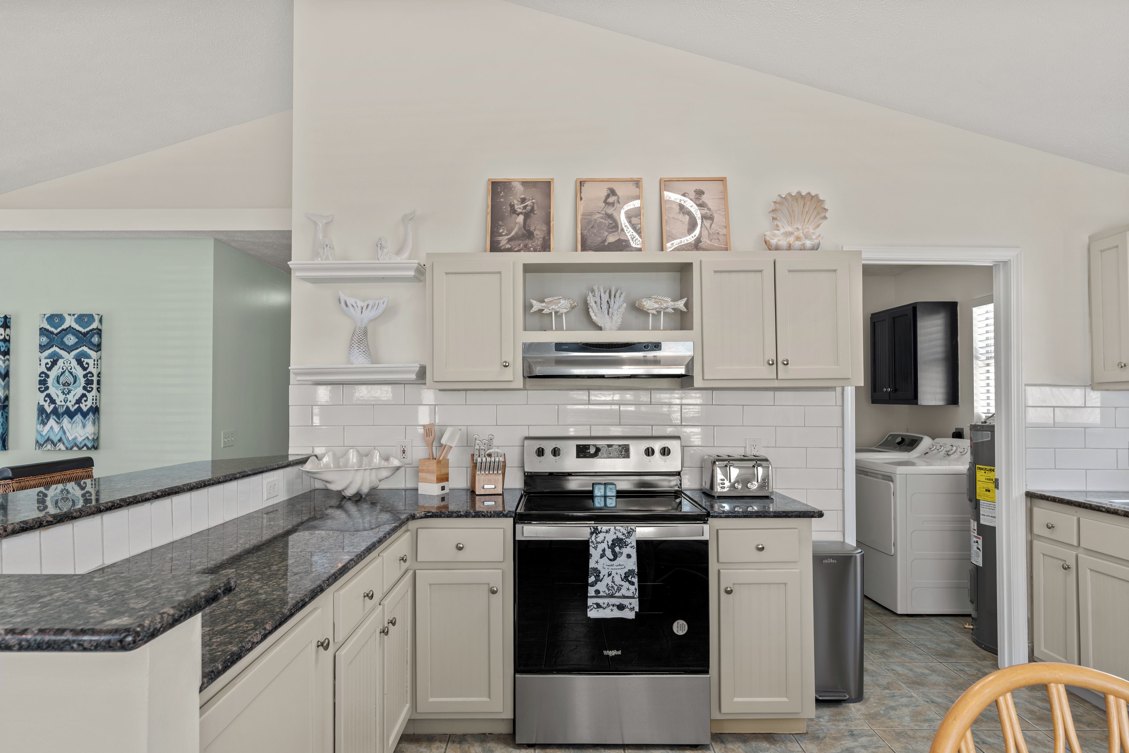 A modern kitchen with a stainless steel stove, white cabinetry, and decorative wall art.
