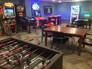A room with a foosball table, several arcade games, and a television screen. - Gorgeous condo with 2 bedrooms/3 bathrooms with ski in / ski out access. (Breckenridge)