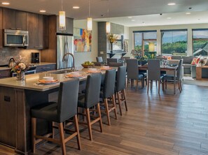 Cocina moderna con una isla central, comedor con sillas y vistas al exterior.