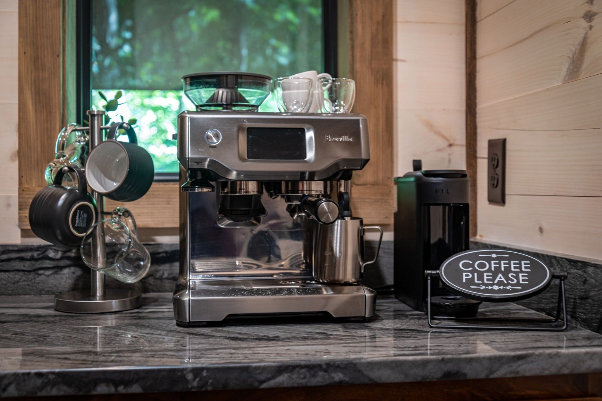 Eine Kaffeemaschine mit einem Schild, auf dem 'Coffee Please' steht, auf einer Marmorarbeitsplatte.