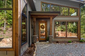 A modern house with large windows, a wooden front door, and a stone entrance. - Otter's Creek - Close to Town | Hot Tub | Fireplace | EV Charger (Blue Ridge)