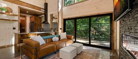 A spacious living area with a leather sofa, ottomans, and a large rug.