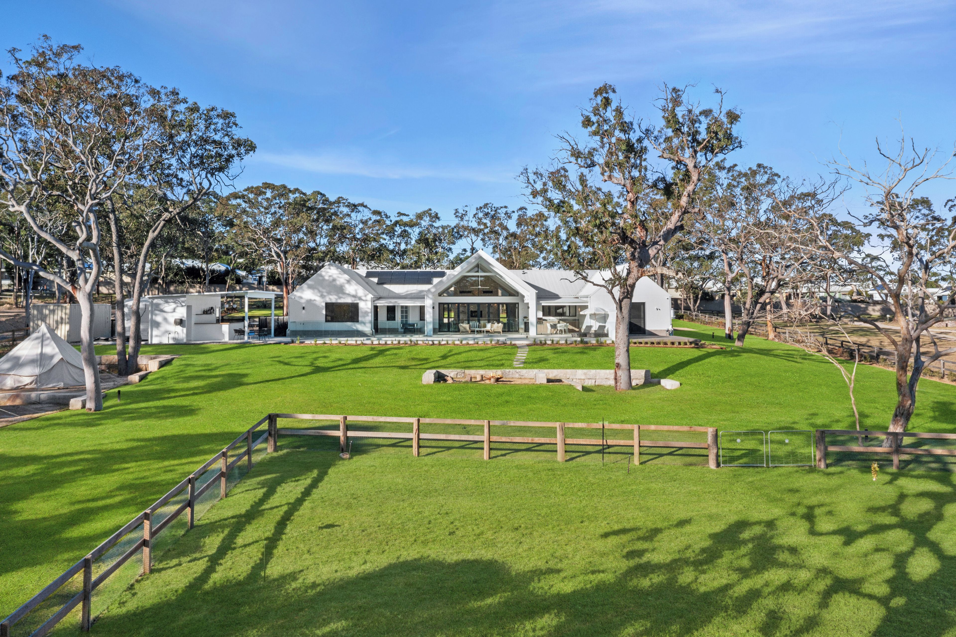 A modern house with a spacious lawn and a wooden fence.