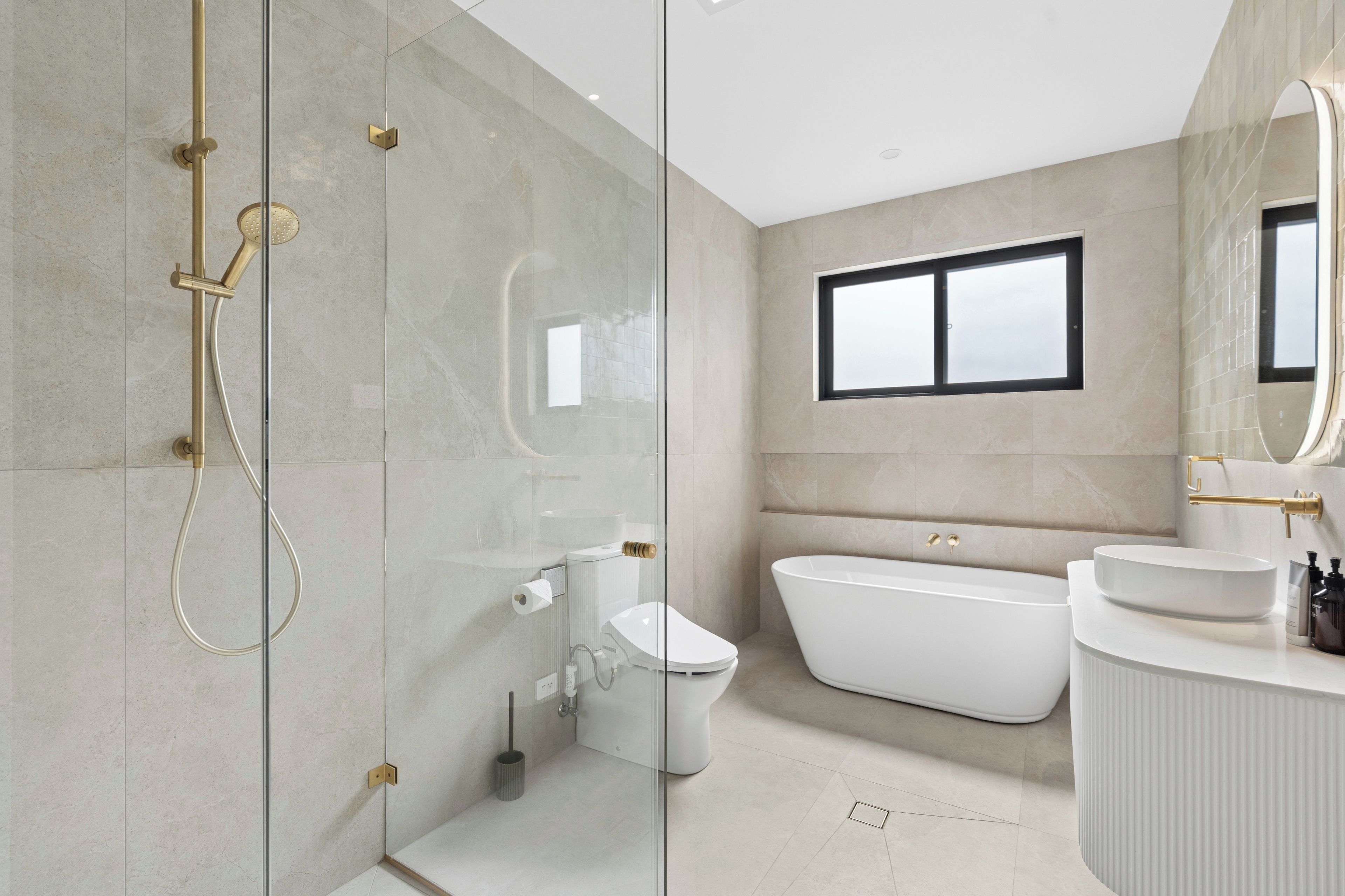 A modern bathroom with a glass-enclosed shower, a freestanding bathtub, and a white sink with a mirror above.