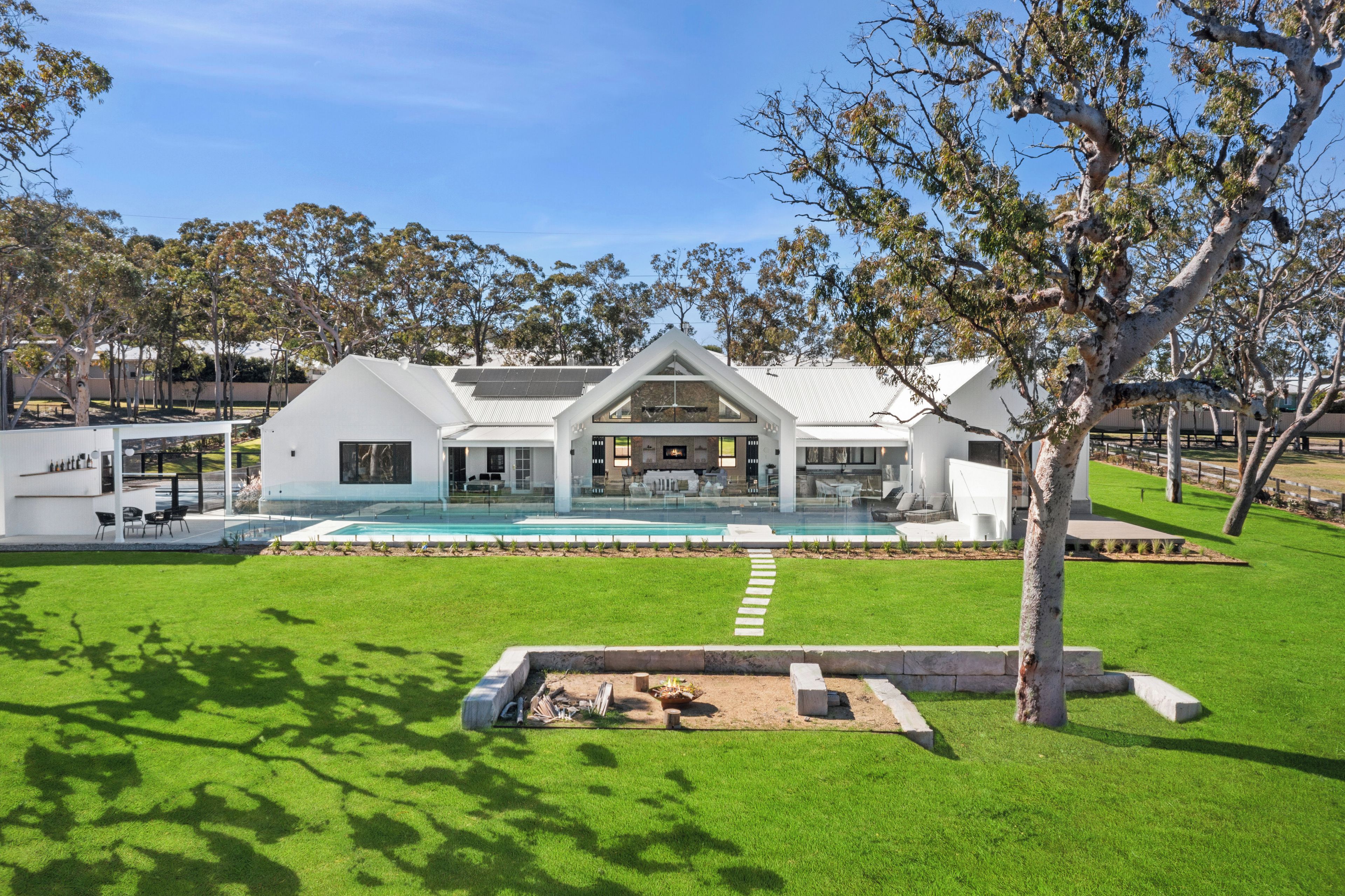 A modern house with a swimming pool, surrounded by a well-maintained lawn and trees.