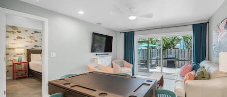 A living room with a pool table, a sofa, and a TV.