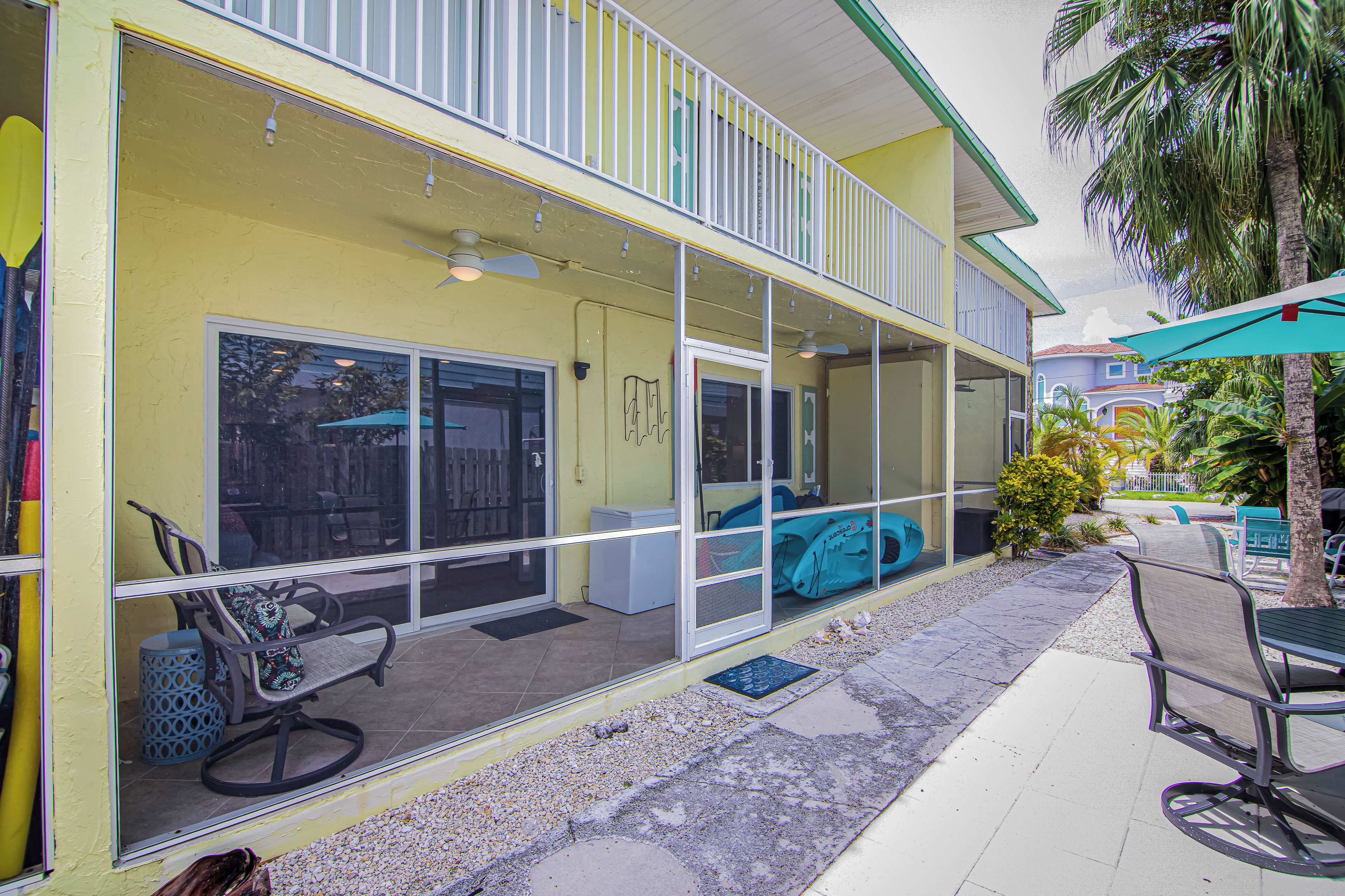 A yellow building with a covered patio area, outdoor seating, and a pool.