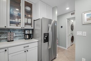 Eine moderne Küche mit einem Edelstahl-Kühlschrank, einer Kaffeemaschine und einem Geschirrspüler.